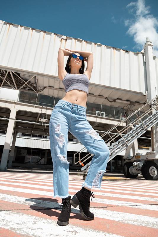 slim latin young woman with black hair posing standing with arms raised,