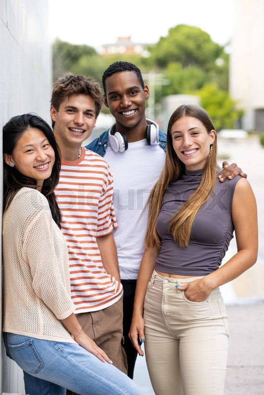 Beautiful young men and women smiling and looking at camera.Diverse group of cheerful millennial people staring relaxed at camera.