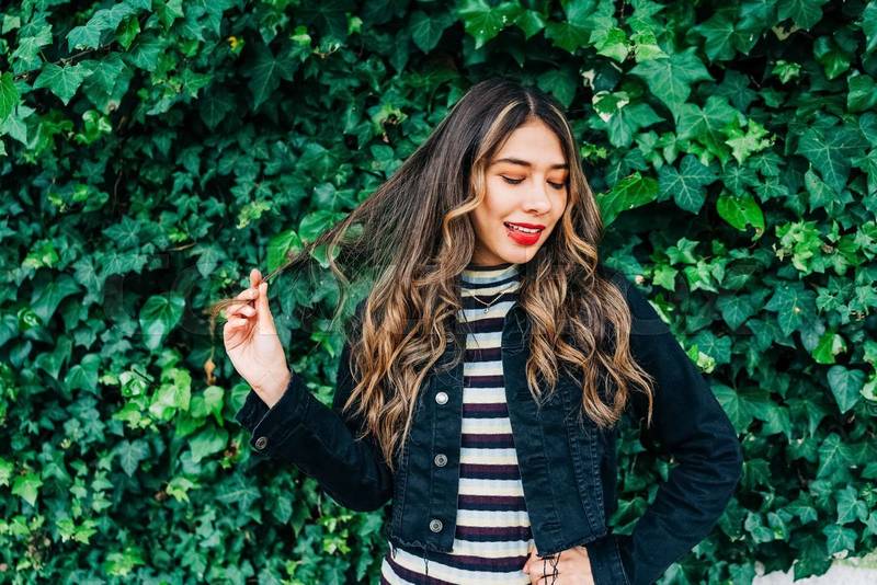 garden with a vine with fresh leaves next to a young latin girl playing