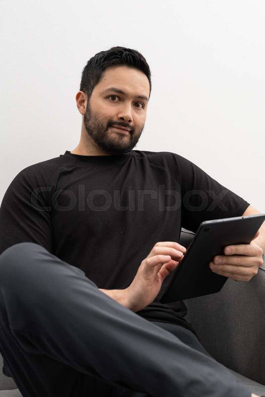 man Focused on his tablet, he appears to be reviewing professional content or reading