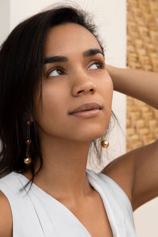 studio the face of a young Latin brunette woman with one hand on her short hair