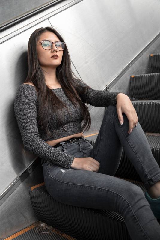 latin woman sitting on some electric stairs, lifestyle beauty