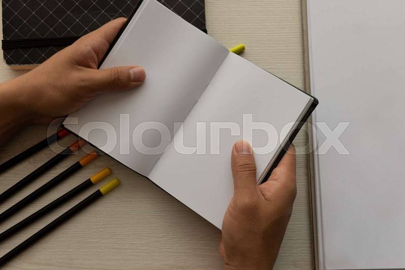 holding an open notebook with blank sheets,  office instruments in workspace