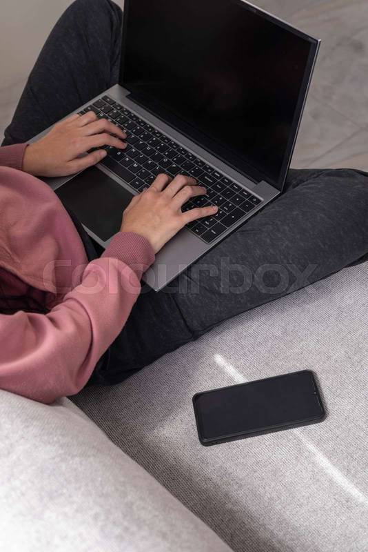 typing on her laptop, working remotely in a calm and comfortable indoor setting.