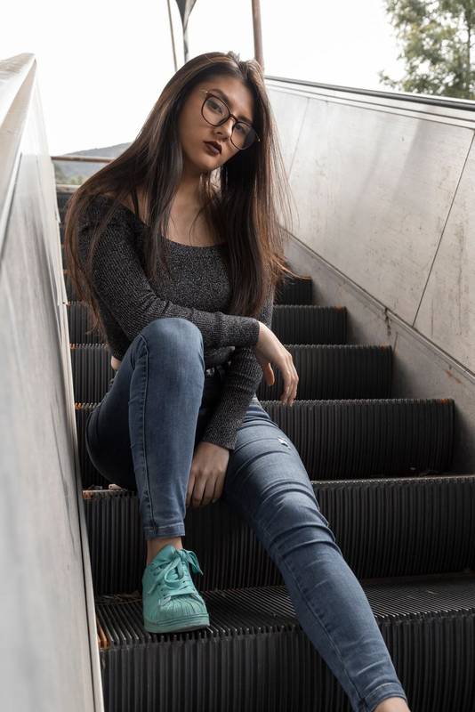 a casual top, is resting sitting on a modern escalator fashion model