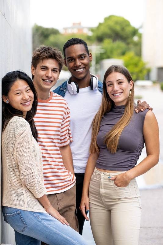 Beautiful young men and women smiling and looking at camera.Diverse group of cheerful millennial people staring relaxed at camera.