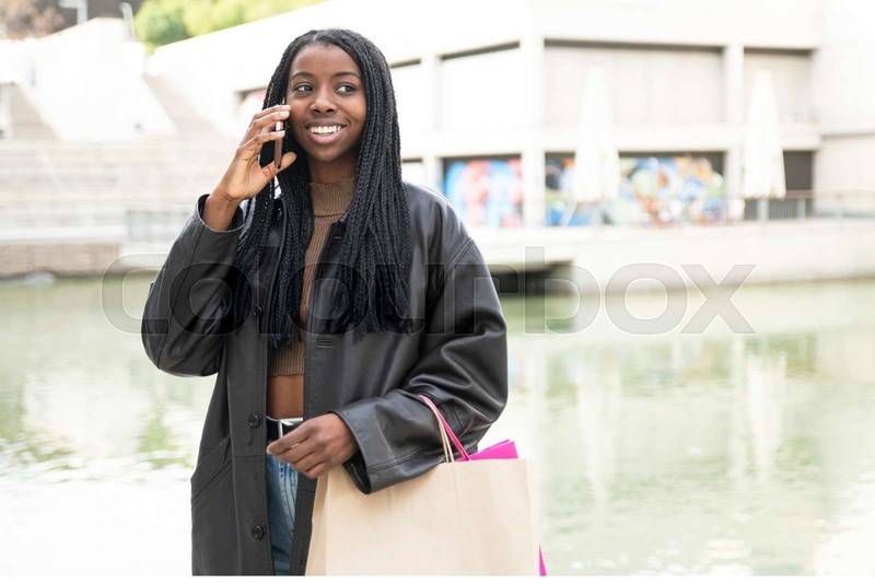 happy young woman using phone with shopping bags at outdoors - fashion, beauty, female concept