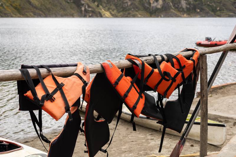 row of colorful life vests hangs from a simple wooden pole, gently swaying in the breeze