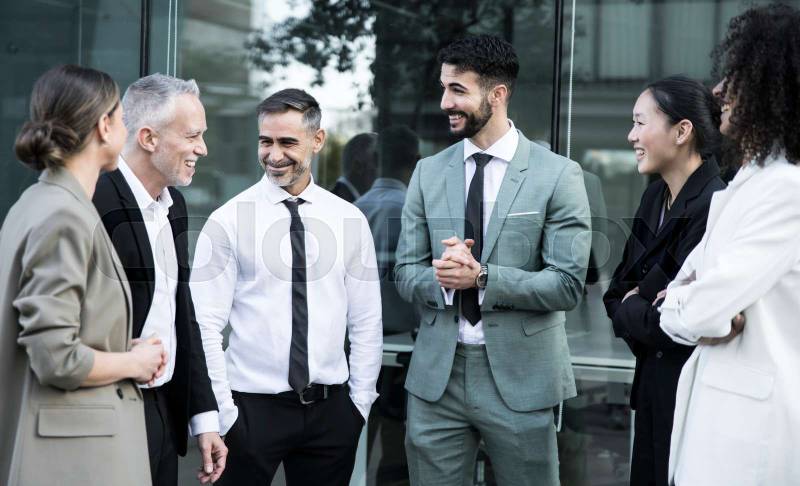 Group of business people group having a casual meeting outdoors. Office colleagues standing in the street discussing and smiling.