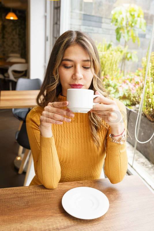 enjoying a cup of coffee a beautiful, young, latin woman