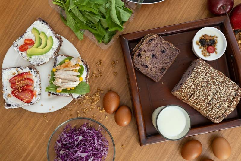 healthy breakfast spread. The plate features the gourmet toast trio with cream cheese, tomato, avocado, and chicken