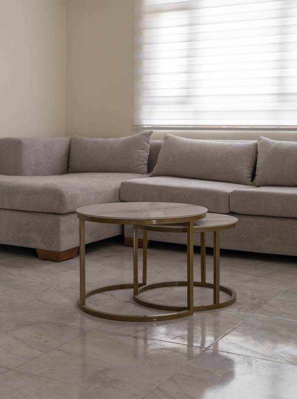 living room interior with a luxurious L-shaped six-seater sofa and a stylish coffee table set composed of two nested tables