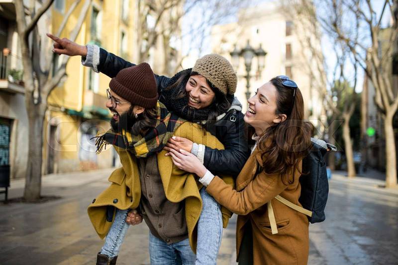 three happy young friends having fun in the city. Multiracial group smiling and looking at camera. Travel concept
