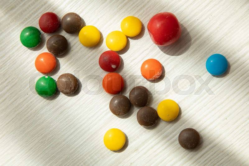 multi colored chocolates on a wooden table, sweet