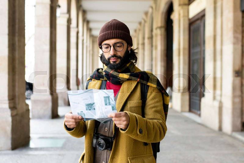 Young tourist holding a map in a city. Happy man with a map outdoors
