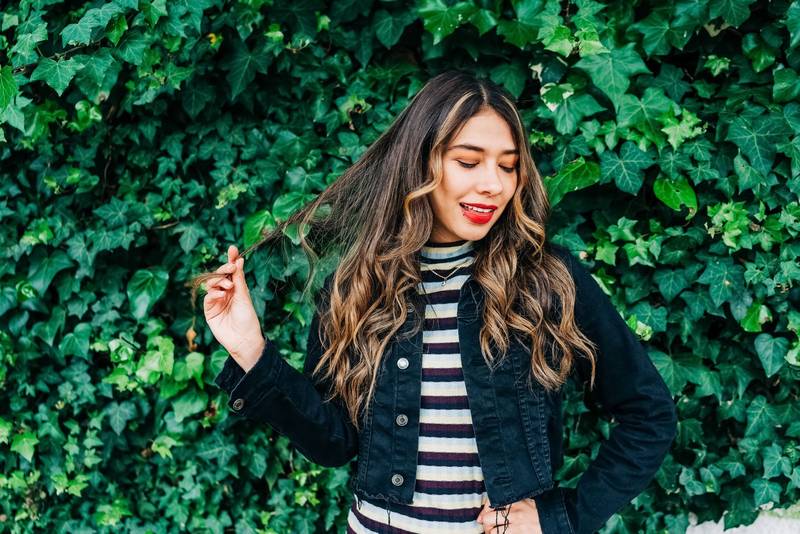 garden with a vine with fresh leaves next to a young latin girl playing