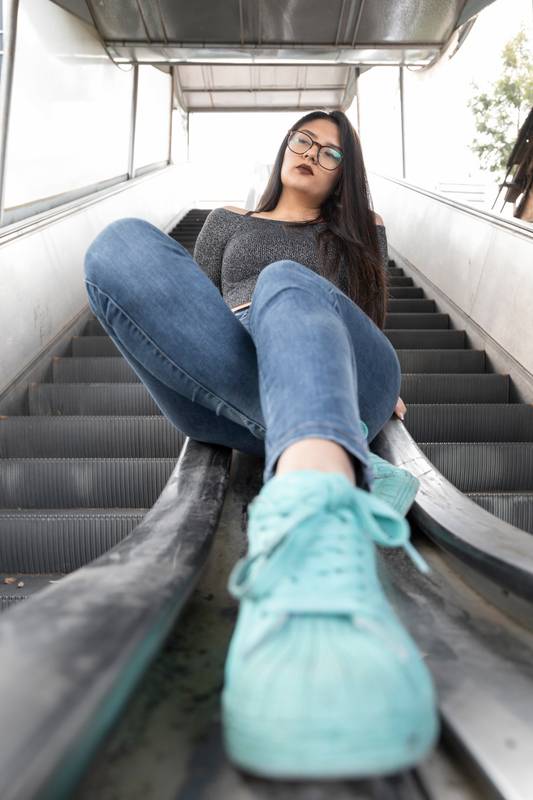 woman sitting on the railing of some electric bleachers in the city, relaxed