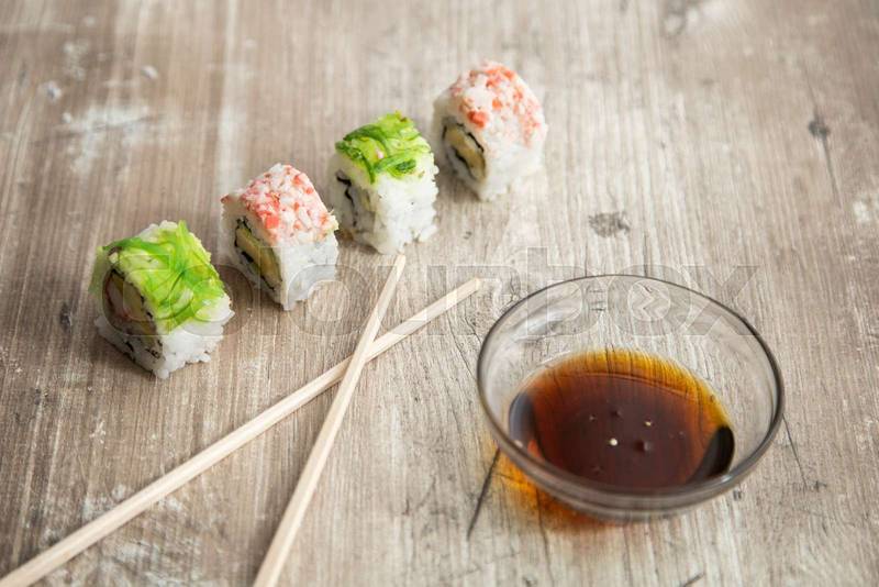 wooden table sushi rolls arranged next to a bowl, apetizer food, delicous snack