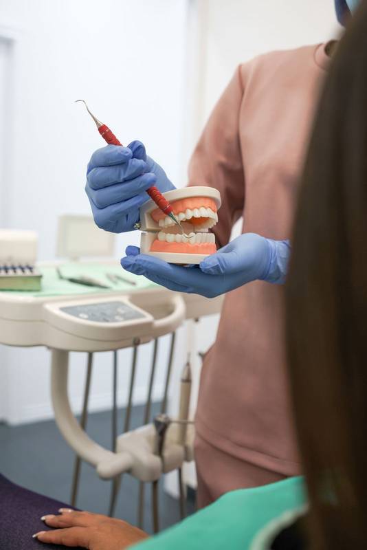 hand with surgical glove holds and shows dental prosthesis