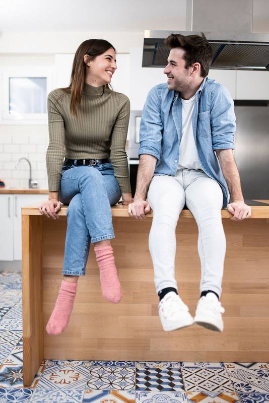 lovely young couple sitting on the kitchen table. Two cheerful young guys smiling at home. love, friendly and confident concept