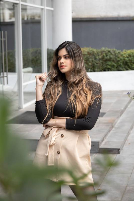 Latina standing near the structure of a building has long blonde hair