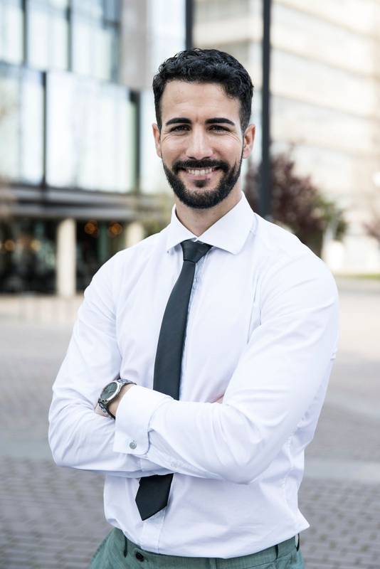 Good-looking businessman looking at camera with arms crossed. Confident and smiley executive standing in front of the camera.