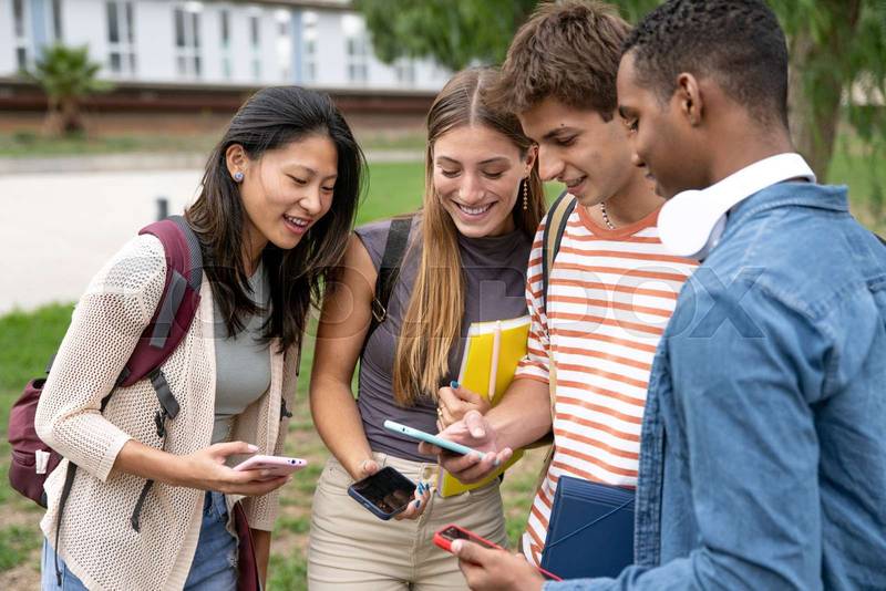 Diverse group of friends checking their phones.Happy multiracial friends using smartphone in a campus.