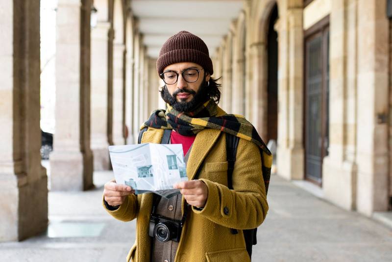 Young tourist holding a map in a city. Happy man with a map outdoors