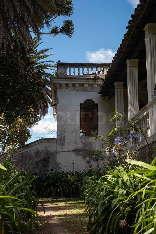 colonial architecture, wooden framed windows, tiled roof, and a vibrant garden full of colorful flowers
