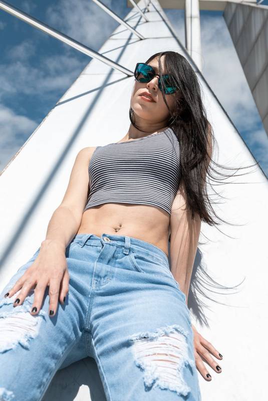 in the city a beautiful slim woman with long black hair, she wears jeans, top and sunglasses, lifestyle