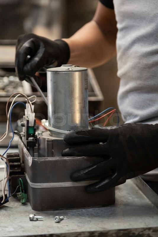 repairing a modern metal object that is on his workplace