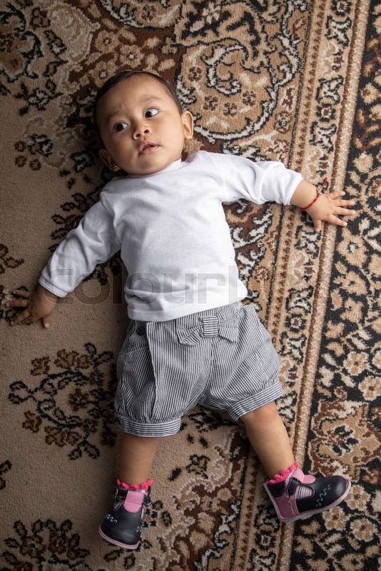 little boy lying on textured rug infant