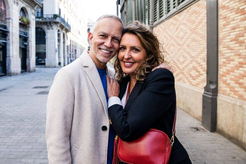 Affectionate senior man and woman hugging happy and relaxed in old town. Lovely mature couple bonding and embracing together looking at camera.