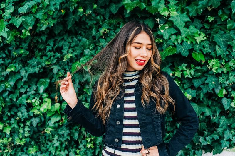 garden with a vine with fresh leaves next to a young latin girl playing