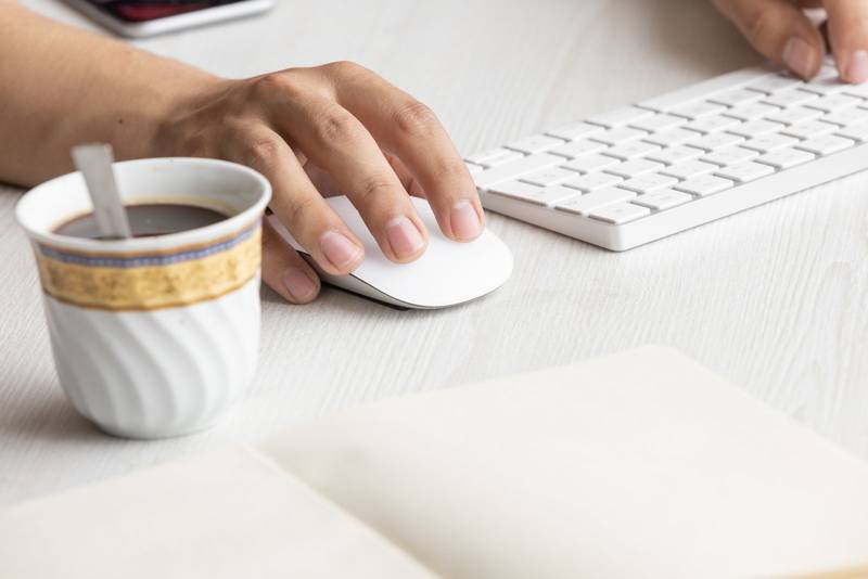 desk with the hands of a person typing on a keyboard and using a mouse