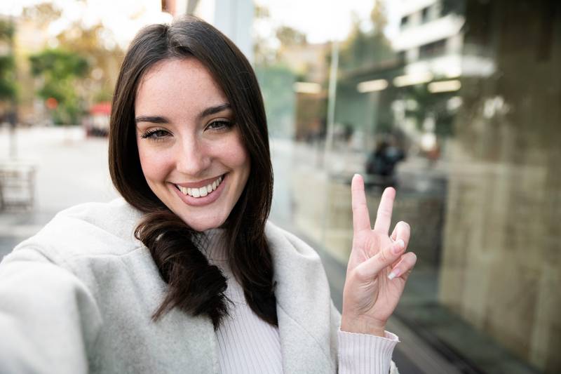 happy smiling beautiful woman taking a selfie in the city - portrait of young girl taking a selfie outdoor