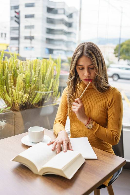 working day of young latin woman with blonde hair, studying a book and taking notes