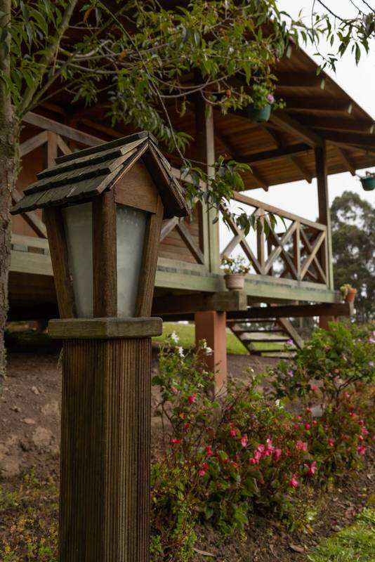 ooden house with balcony next to a beautiful garden and a lamp