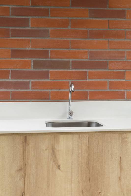 hand basin with a modern tap, space decorated with a brick wall and wooden furniture