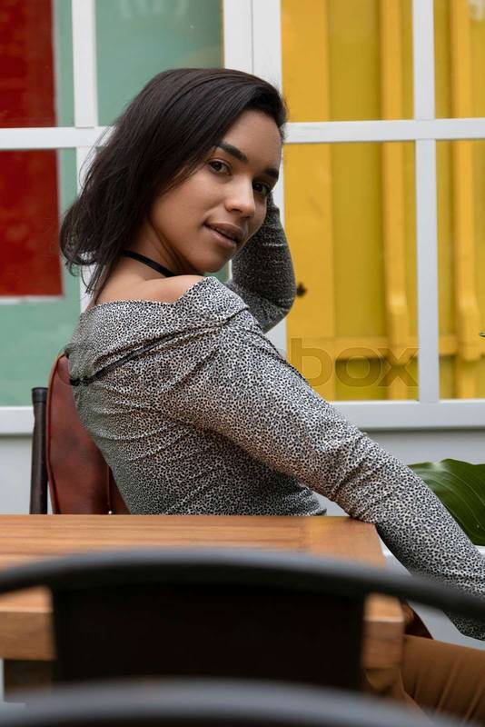 woman, young latina with short hair sitting by a table, wearing casual clothes
