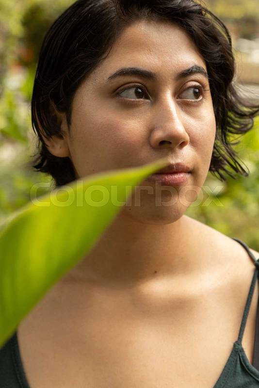 young latin woman with short hair, smiling with a leaf in the shot, natural beauty