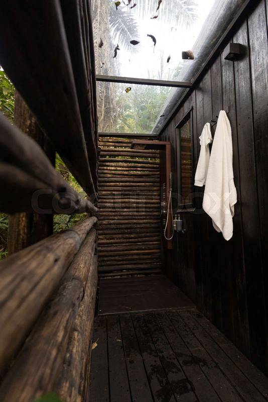 In a forest-inspired bathroom with bamboo-textured walls, soft white towels hang peacefully
