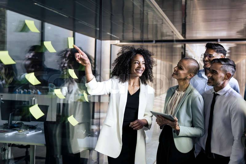 Group of business people doing presentation using post it. Businesswoman leading a team meeting