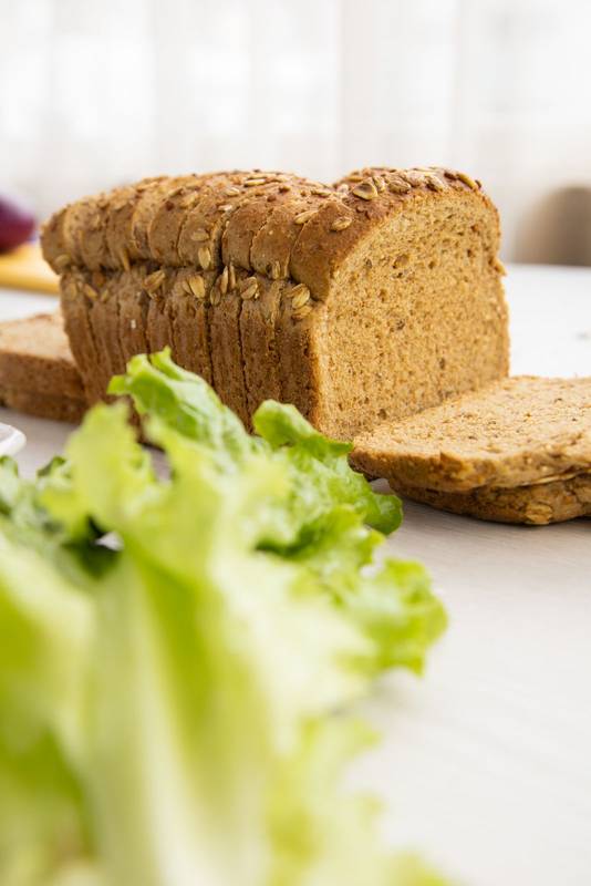 sliced whole wheat bread mold next to a lettuce, healthy food ingredients in studio