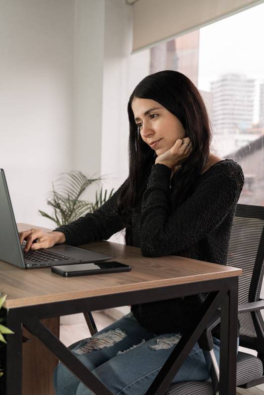 Woman smiling while working on laptop in a shared office. Calm, focused environment with modern style