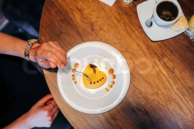 person hand holding a spoon eating a heart shaped cake