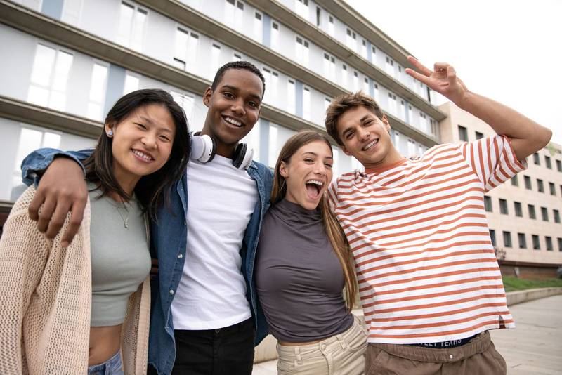 Happy multiracial group of friends having fun looking at camera.Diverse cheerful young people laughing standing outside.