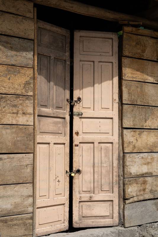 aged wooden door stands at the entrance of an old house