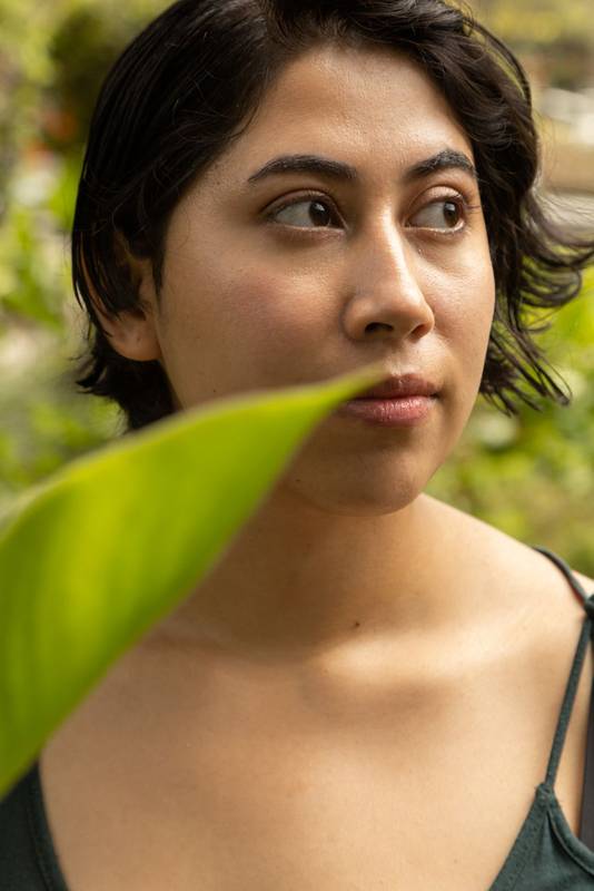 young latin woman with short hair, smiling with a leaf in the shot, natural beauty