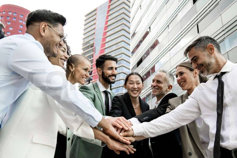 Group of smiling multiethnic businessman and businesswoman holding hands together outside. Multiracial cheerful successful executive team standing in a circle. Teamwork concept.